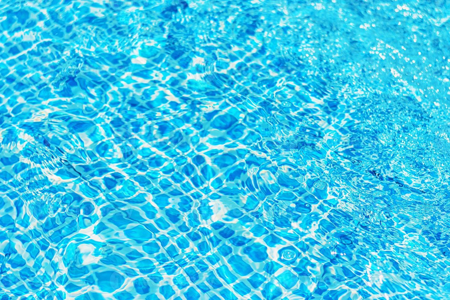 superficie dell'acqua increspata in piscina con riflesso del sole foto