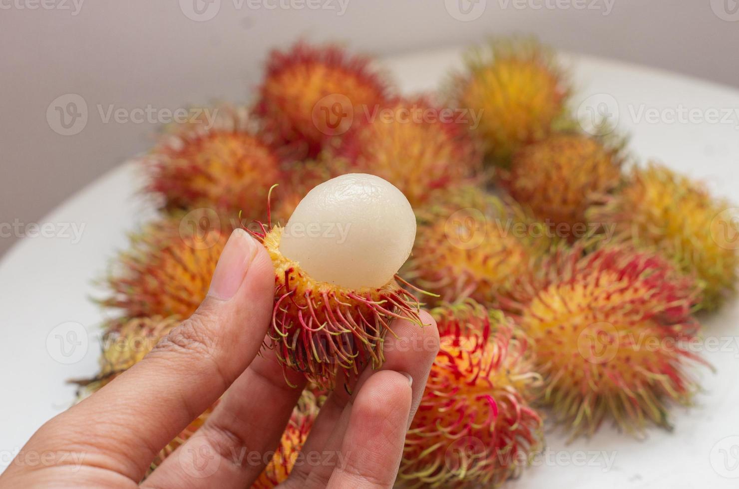 mano che tiene un rambutan sbucciato foto