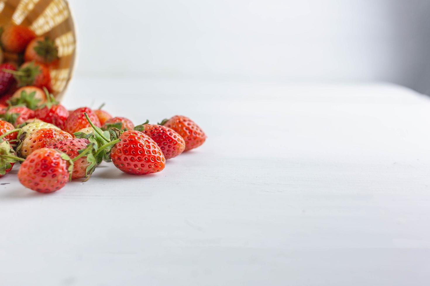 fragole fresche in un cesto su sfondo bianco foto