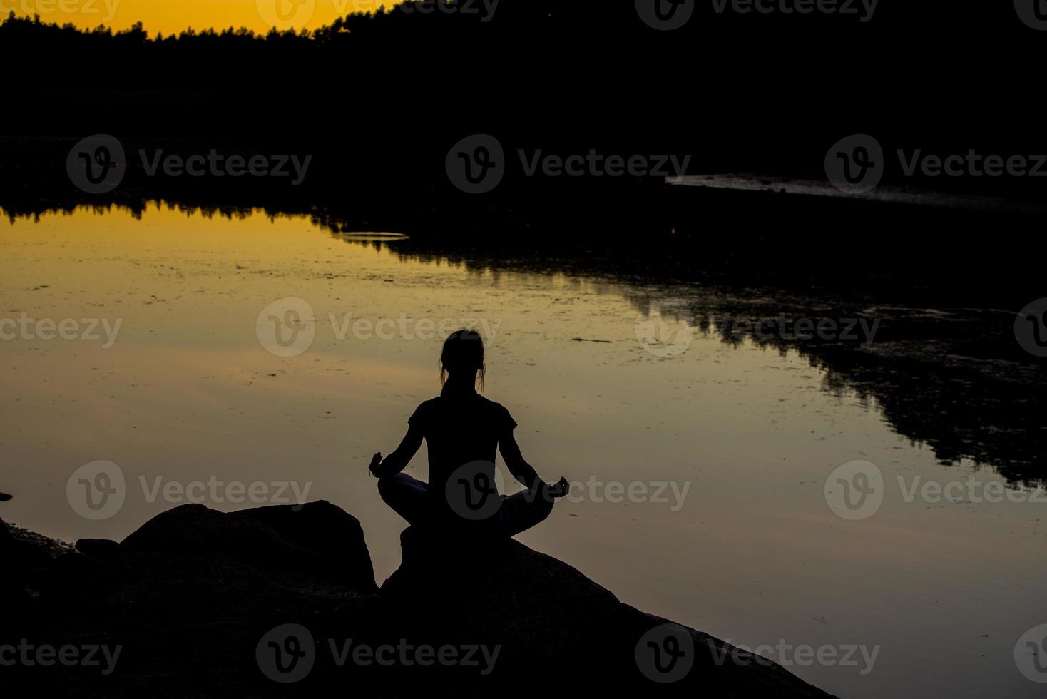 sagome di una donna che fa yoga al tramonto foto