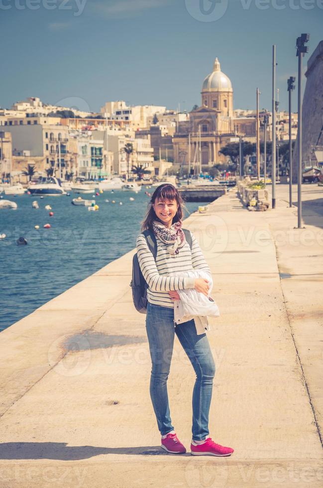 giovane ragazza viaggiatore soggiorno e posa sull'argine del torrente kalkara del grande porto di malta foto