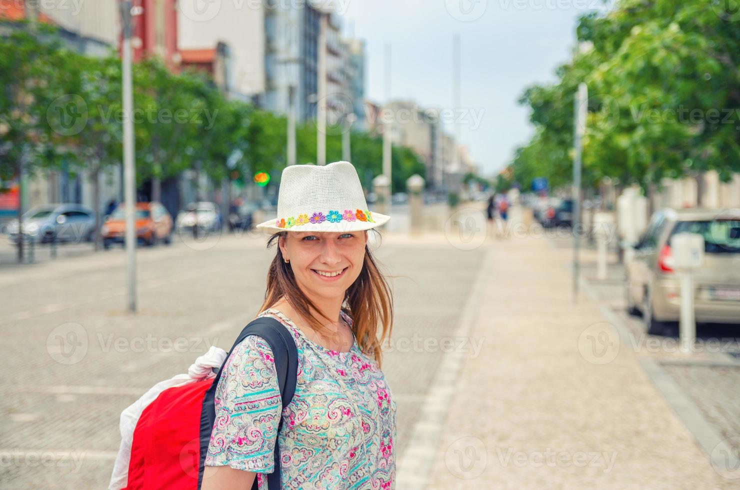 viaggiatore di giovane donna con cappello che guarda l'obbiettivo in posa e sorridente nelle strade della città di aveiro in portogallo foto