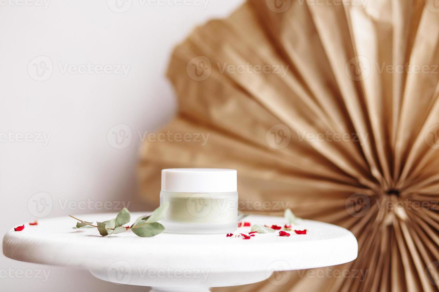 maschera cosmetica in polvere. vasetto di vetro con matcha su fondo bianco con petali secchi. foto