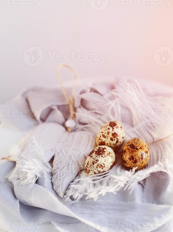 uova di Pasqua con piuma bianca su sfondo bianco e grigio. buone vacanze di pasqua, vista frontale dall'alto. foto