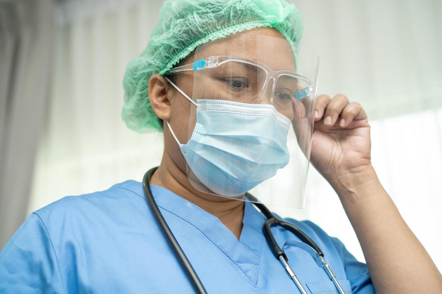 medico asiatico che indossa visiera e tuta dpi nuovo normale per controllare il paziente proteggere la sicurezza infezione covid 19 focolaio di coronavirus nel reparto ospedaliero di quarantena foto