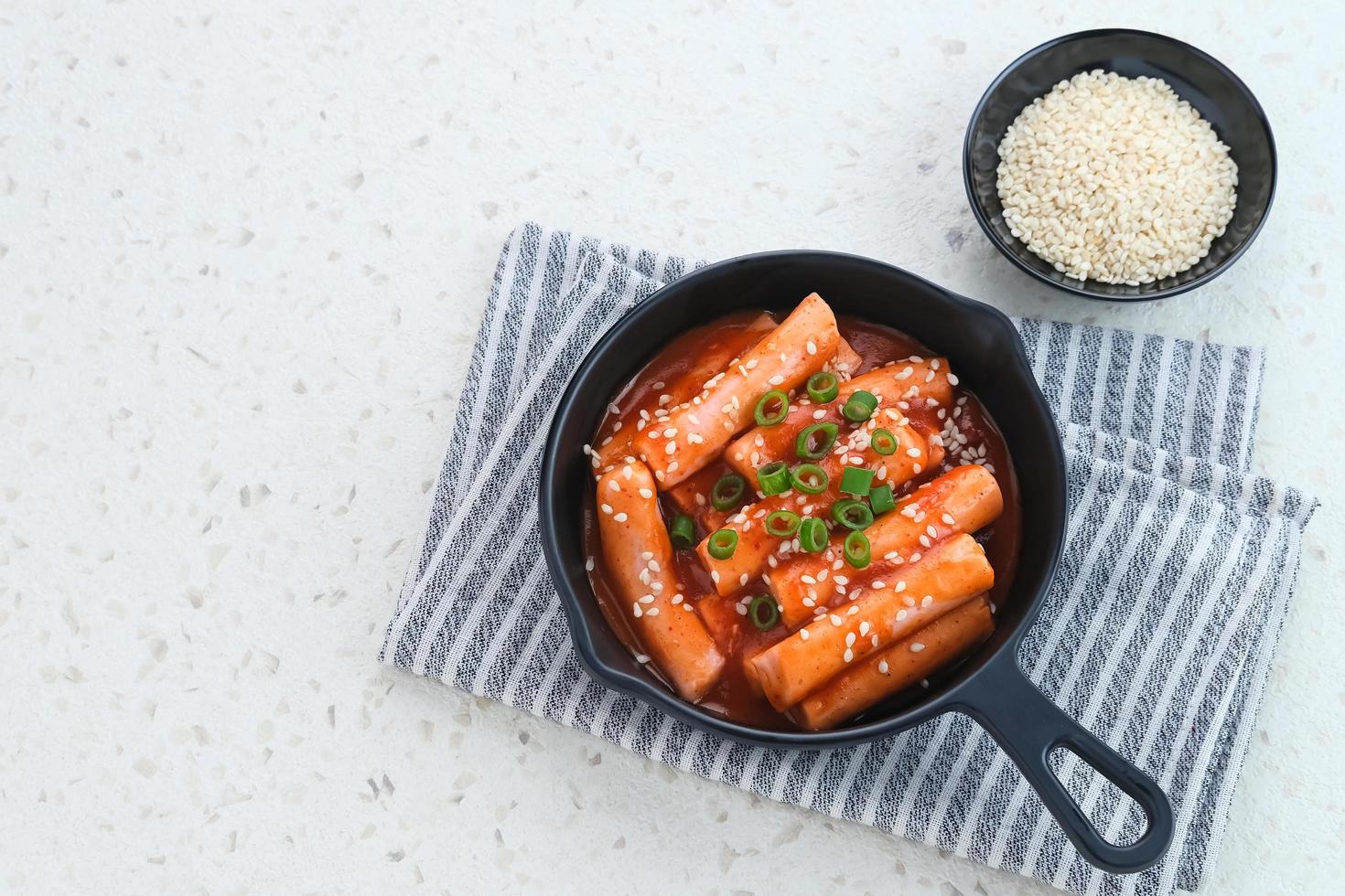 tteokbokki o topokki, bastoncini di torta di riso saltati in padella, popolare street food coreano con salsa gochujang piccante e semi di sesamo. foto