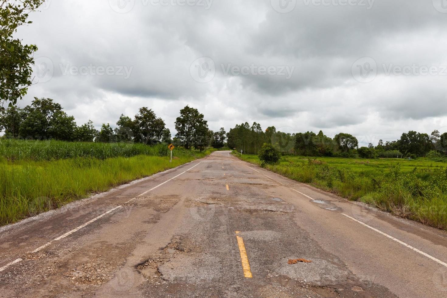 strada asfaltata danneggiata con buche foto