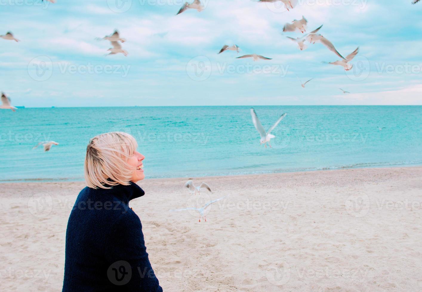 donna bionda e gabbiani in una giornata nuvolosa sulla costa del mare foto