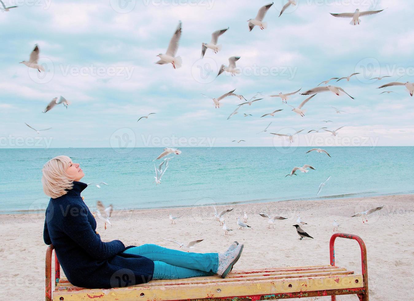 donna bionda e gabbiani in una giornata nuvolosa sulla costa del mare foto