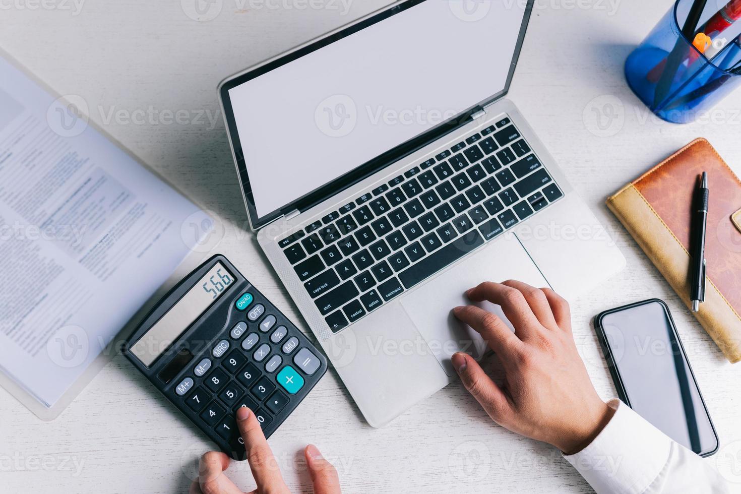 gli uomini d'affari asiatici usano una calcolatrice per calcolare le tasse e il reddito foto