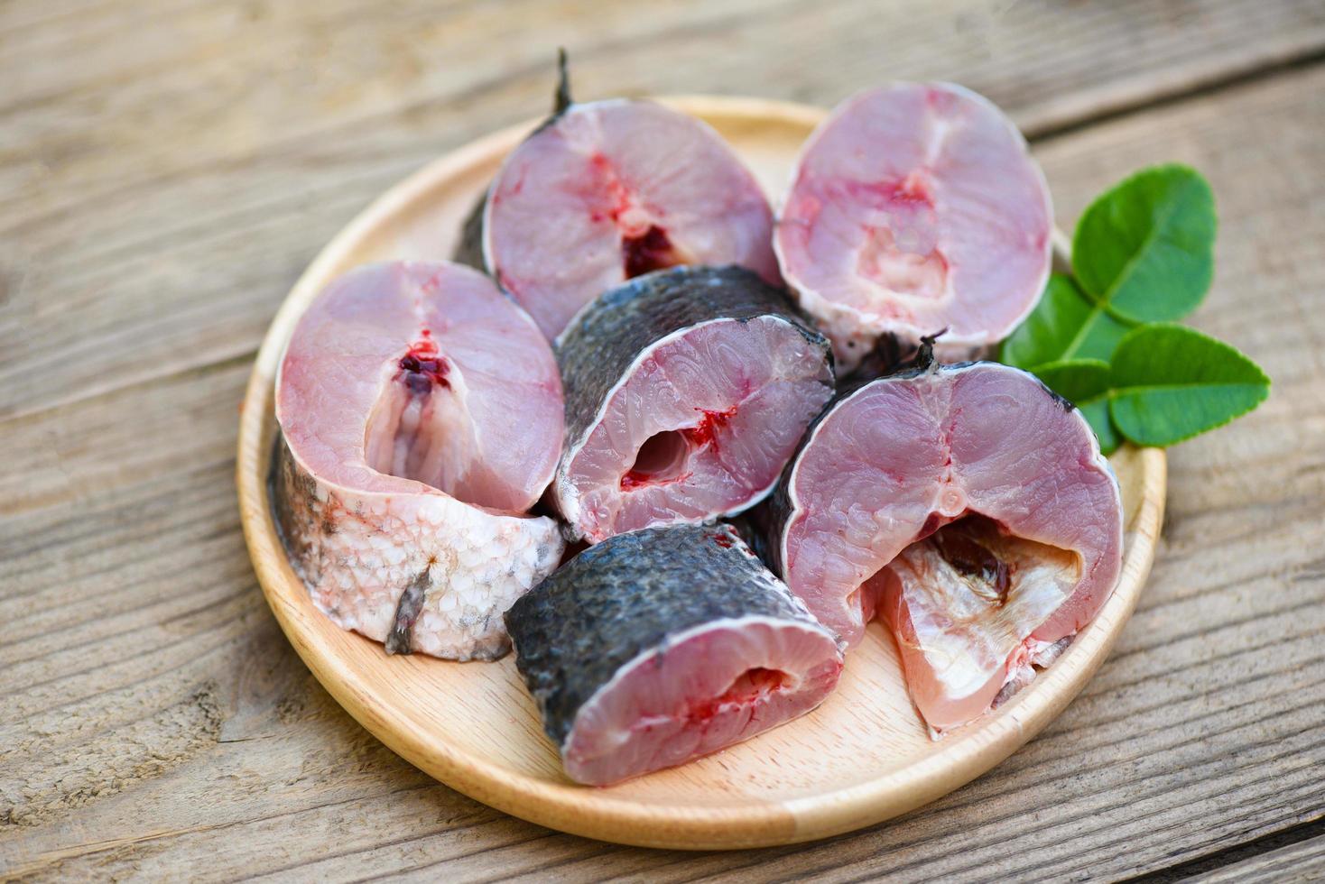 menu di pesce testa di serpente crudo fresco pesce d'acqua dolce, pesce testa di serpente per cucinare cibo, pesce testa di serpente a strisce tritato con ingredienti foglie di lime kaffir sul piatto e tavolo in legno sfondo cucina foto