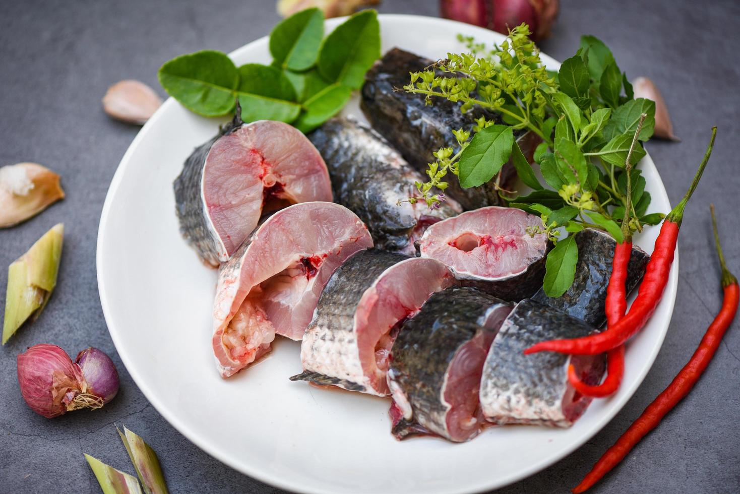 menu di pesce fresco crudo testa di serpente pesce d'acqua dolce, pesce testa di serpente per cucinare cibo, pesce testa di serpente a strisce tritato con ingredienti erbe e spezie su piatto bianco e tavolo sfondo cucina foto