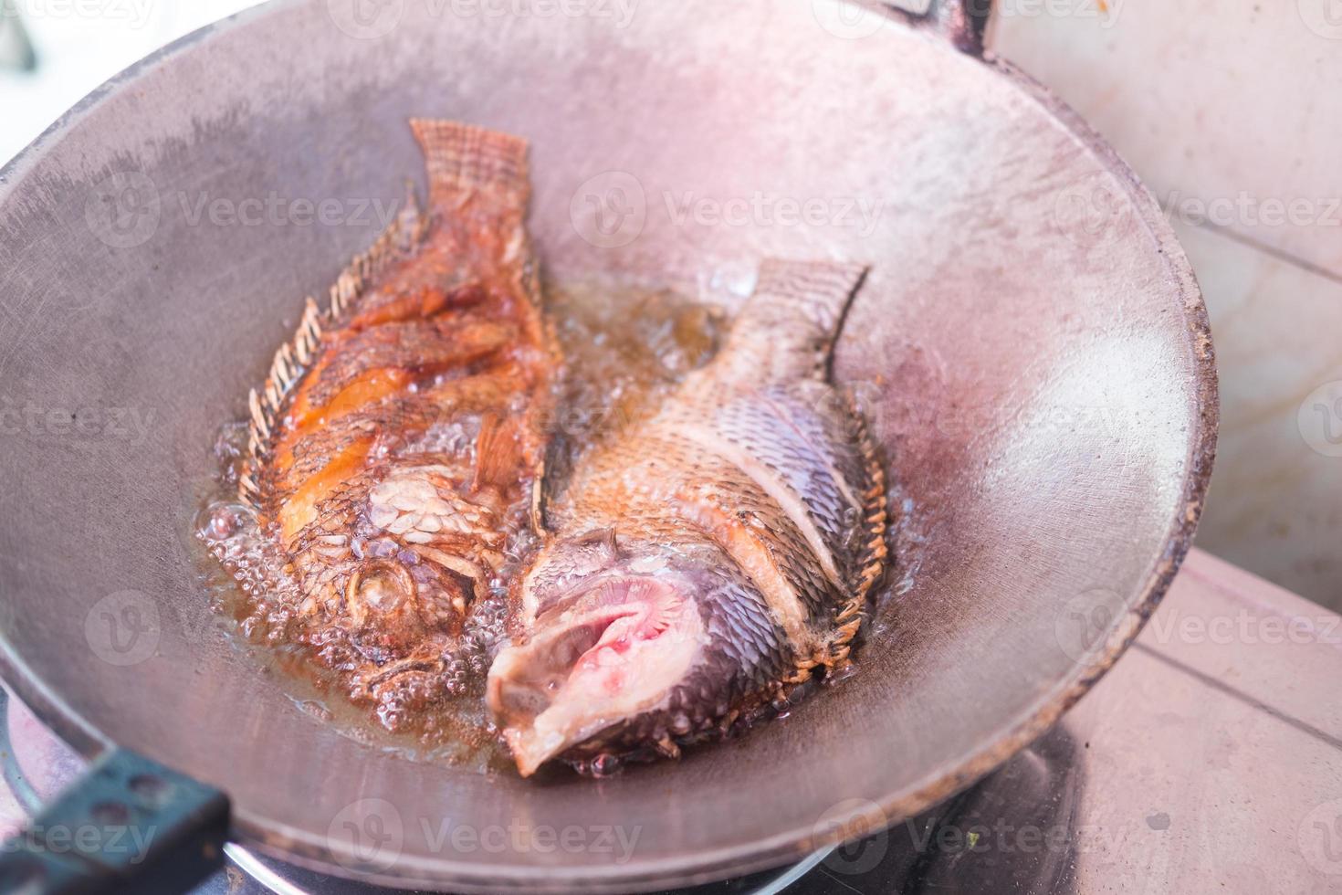 friggere il pesce tilapia in padella d'acciaio foto