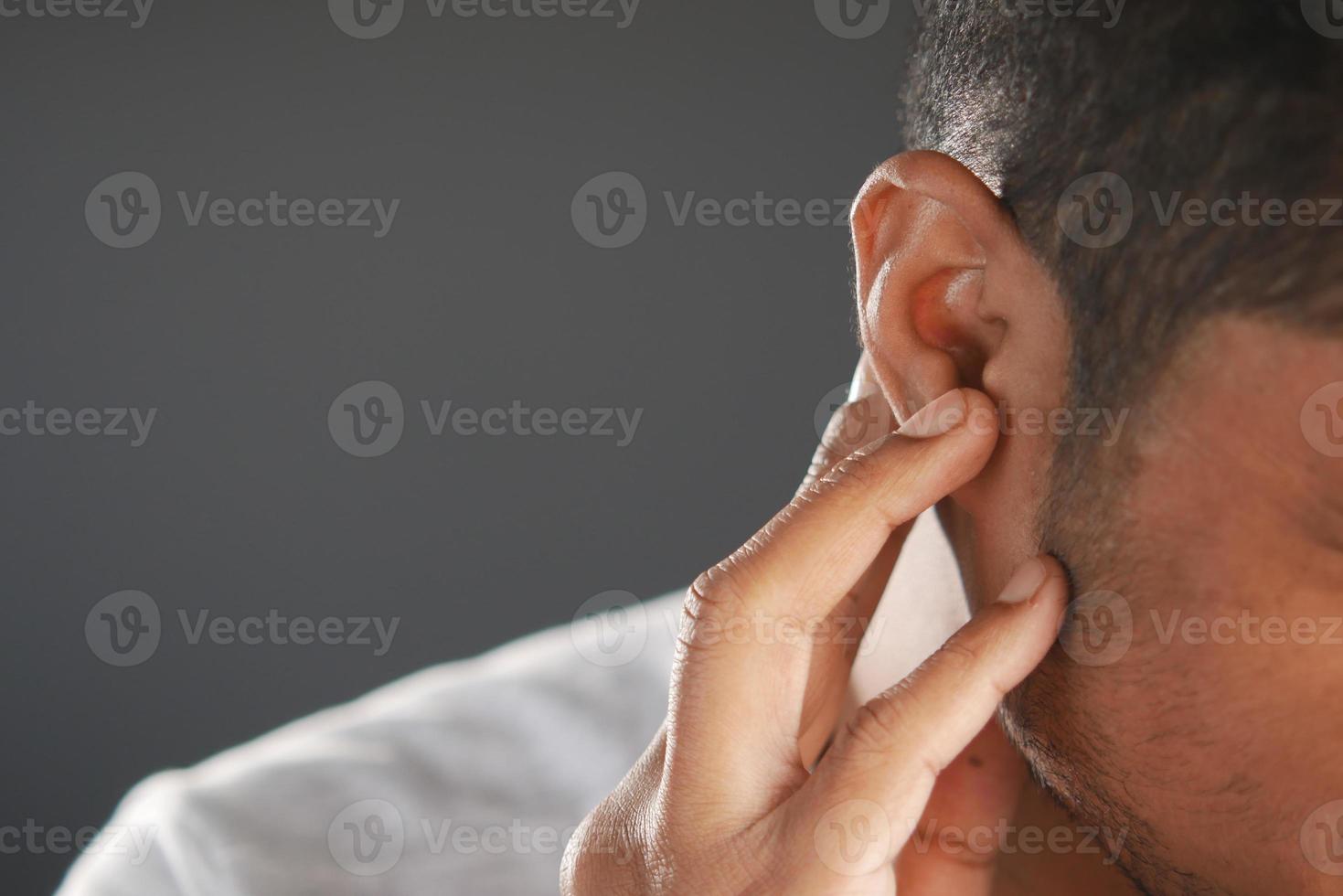 giovane che ha dolore all'orecchio che tocca il suo orecchio doloroso, foto