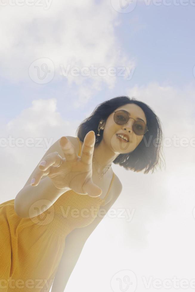 ritratto di donna asiatica sorridente felice con vista cielo blu dal basso. foto