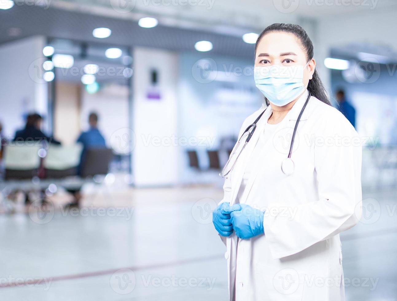 donna medico si trova di fronte a una stanza d'esame in un ospedale. concetto di cure mediche assistenza sanitaria controllo sanitario annuale bellezza, ricerca, laboratorio, scienza, primo piano, copia spazio, sfondo sfocato foto