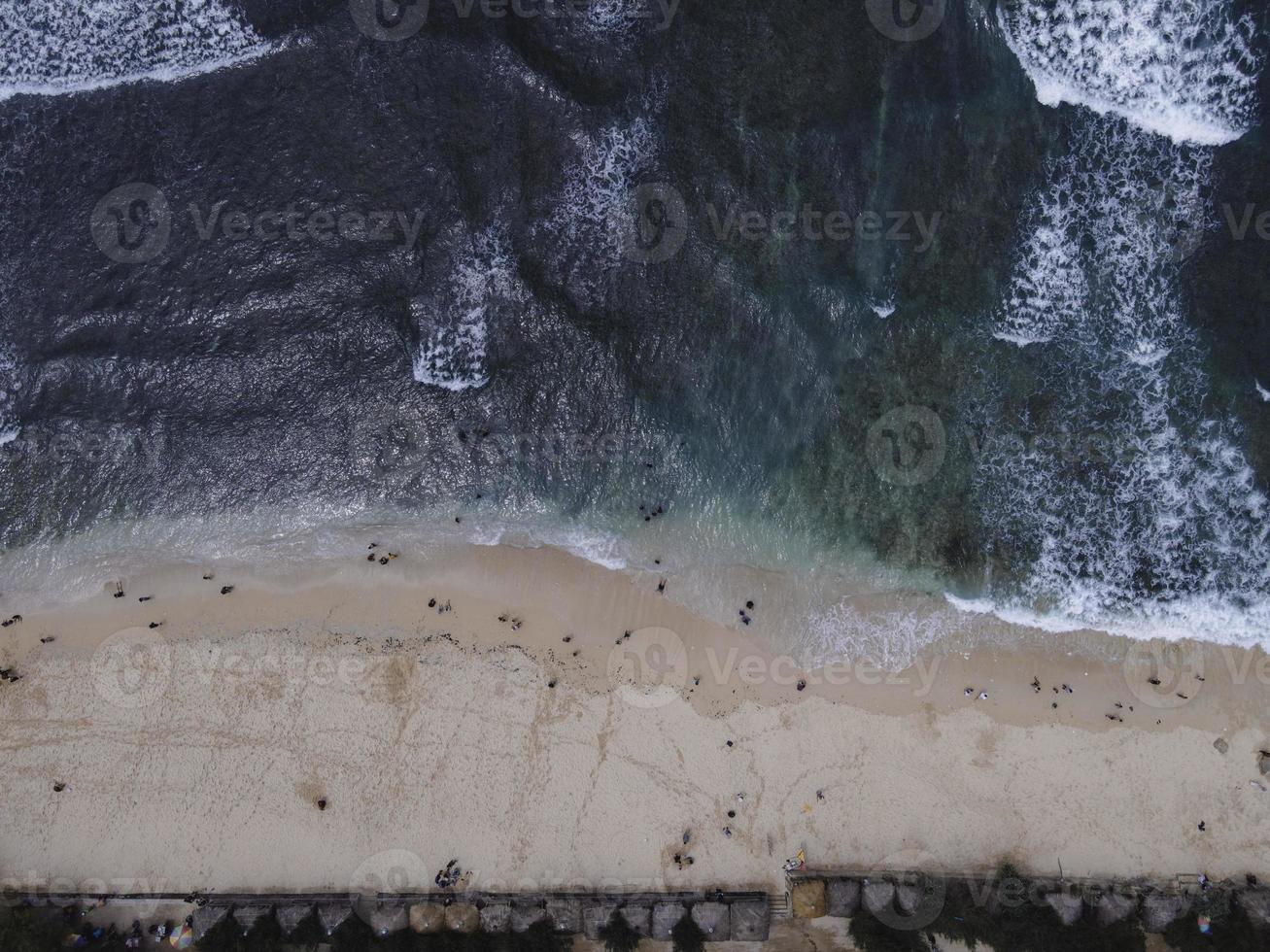 vista aerea del drone della vacanza nella spiaggia di gunung kidul, in indonesia con oceano, barche, spiaggia e persone. foto