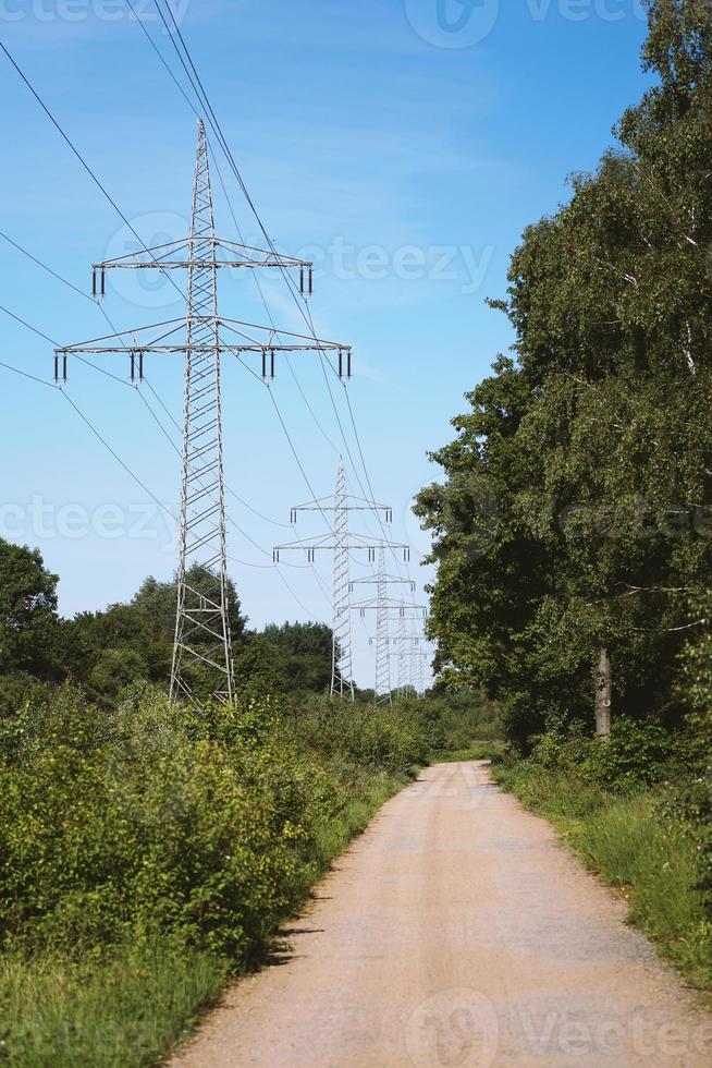 linea di trasmissione o cavo elettrico aereo lungo un sentiero sterrato rurale attraverso la campagna foto