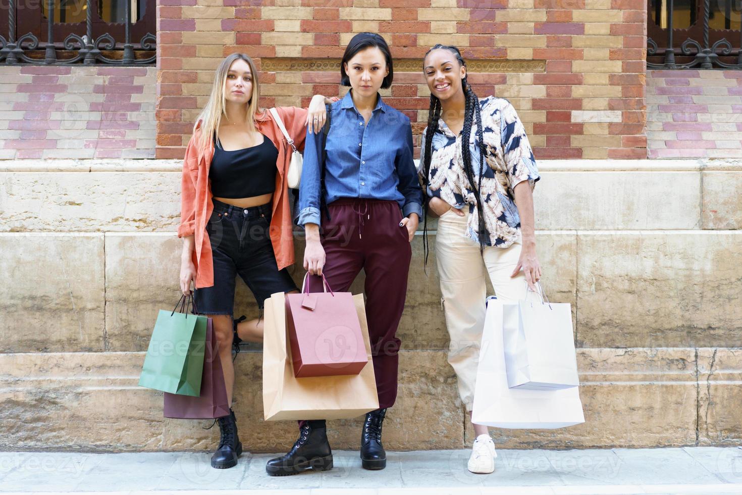 eleganti giovani diverse amiche in piedi sulla strada dopo lo shopping foto