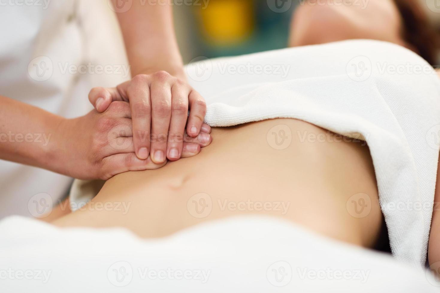 terapista che esercita pressione sulla pancia. mani che massaggiano l'addome della donna. foto