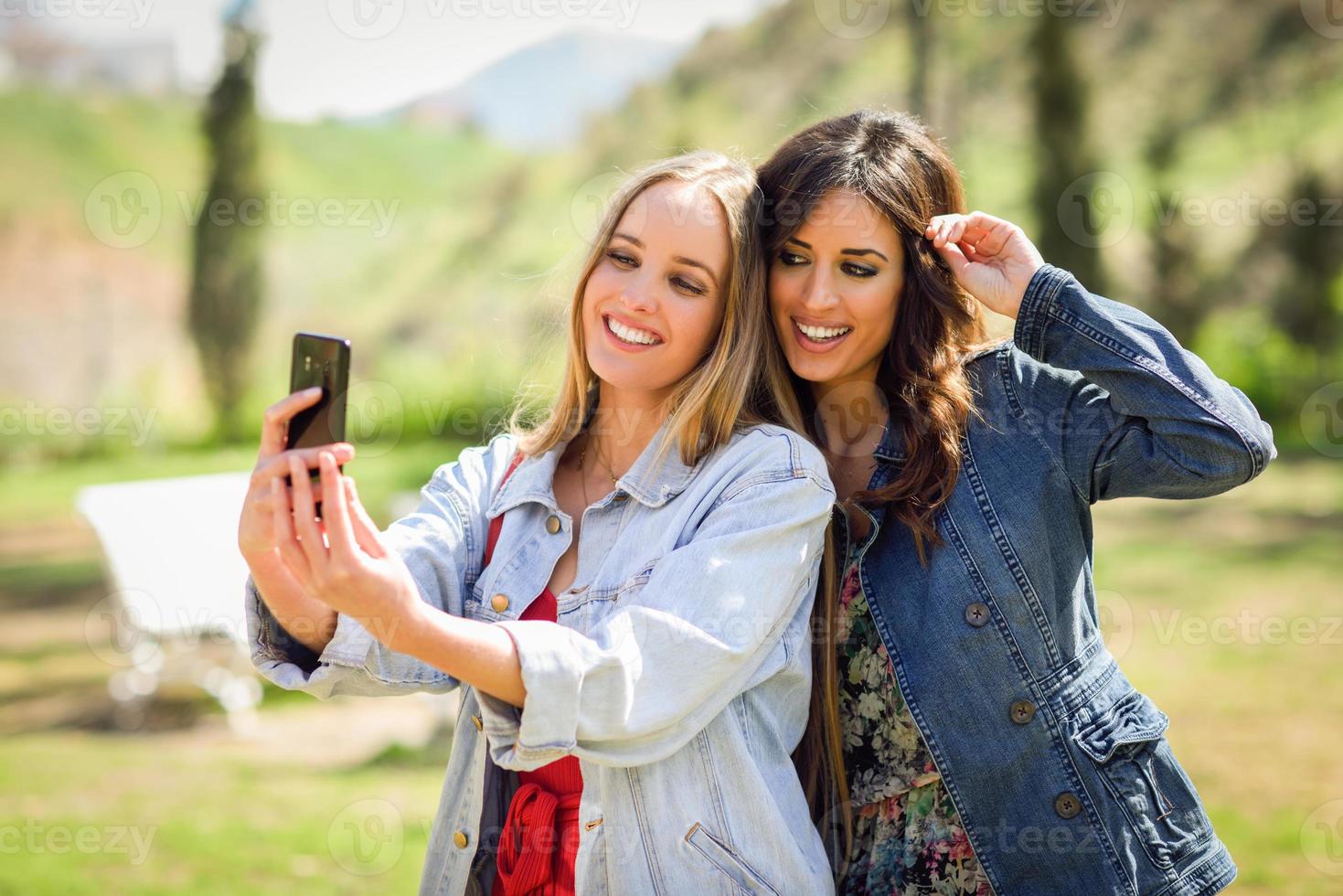 due giovani donne che scattano una fotografia selfie nel parco urbano foto