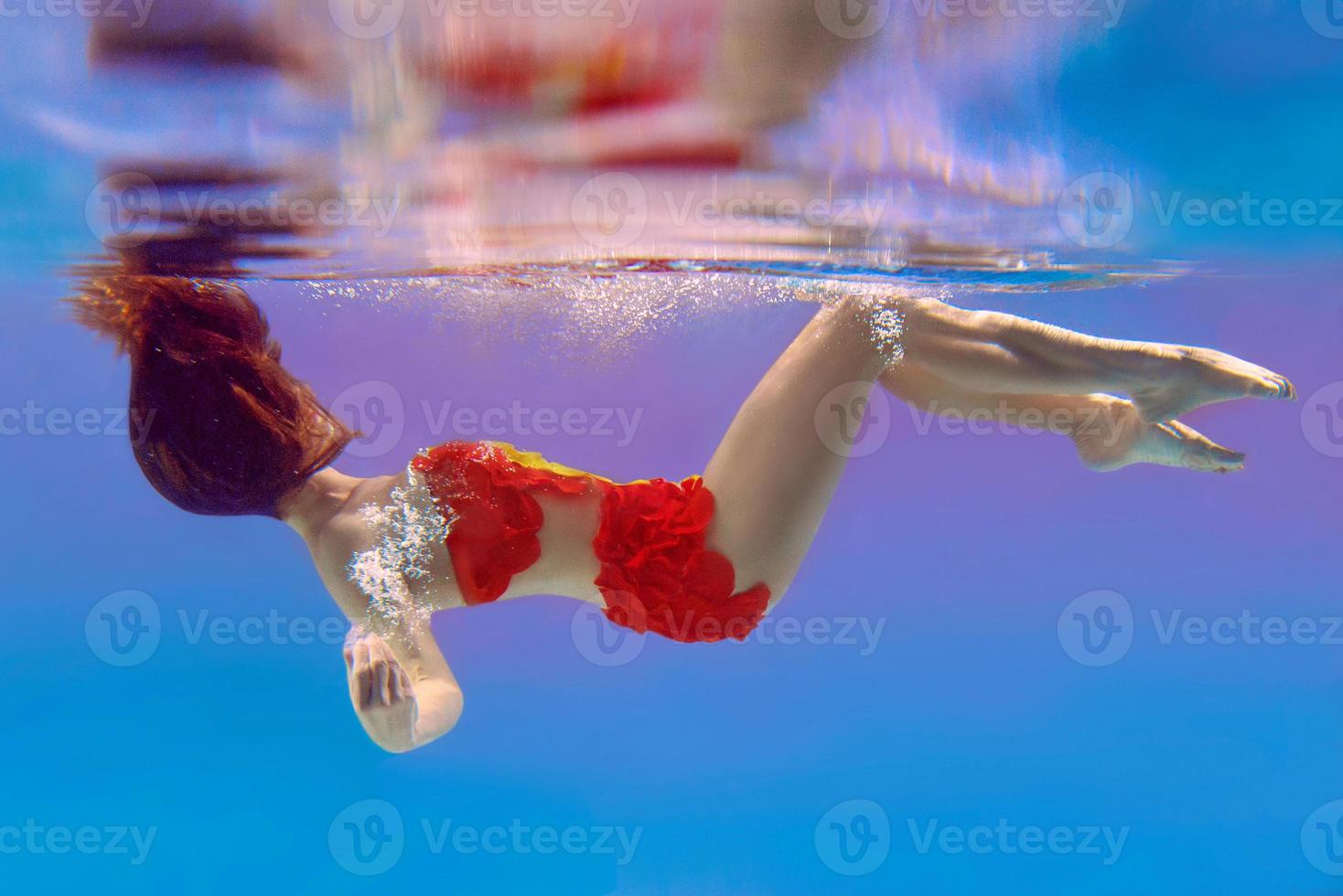 incredibile, surreale, incredibile, incredibile ritratto subacqueo di donna snella e in forma in costume da bagno arancione brillante foto