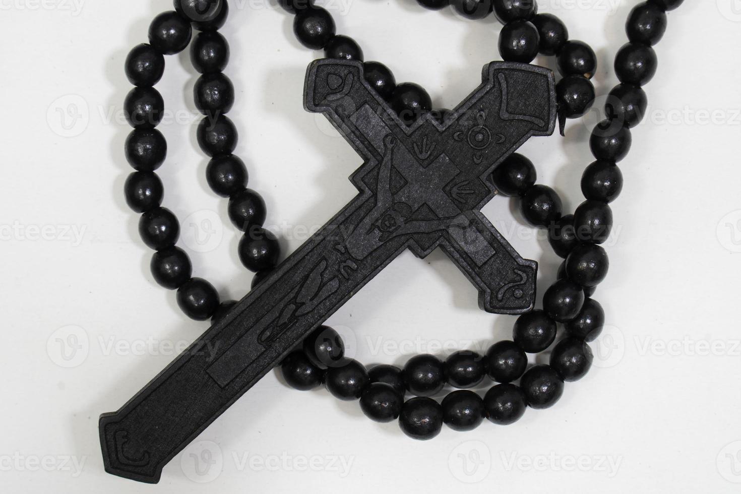 rosario con croce in legno nero su sfondo bianco, fuoco selezionato su cristo, profondità di campo ridotta. foto