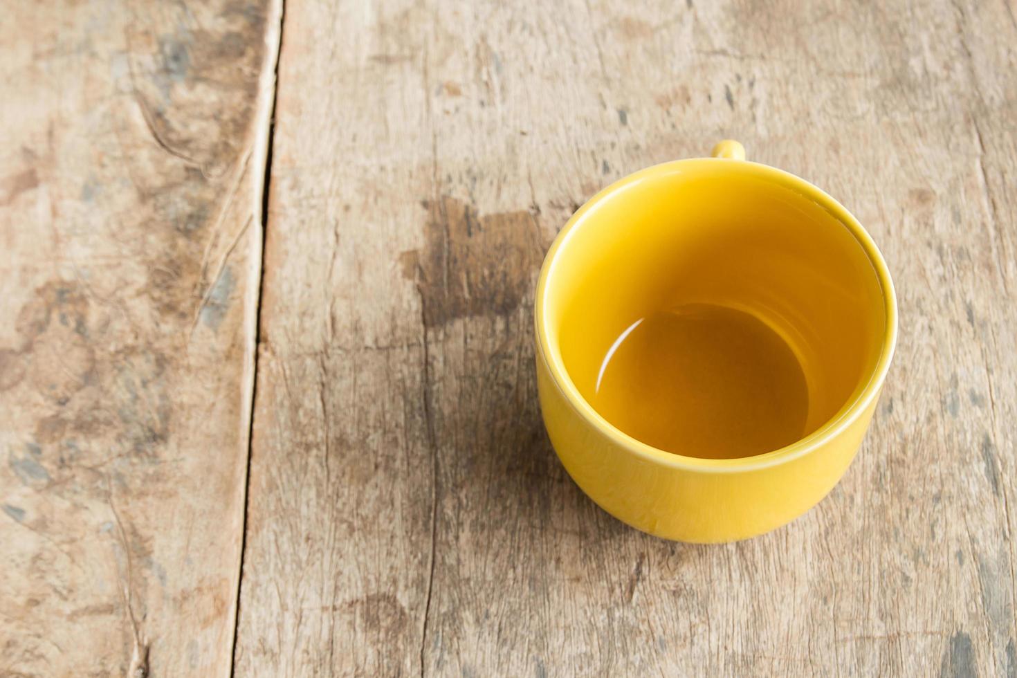 tazza di caffè gialla sul vecchio tavolo di legno foto