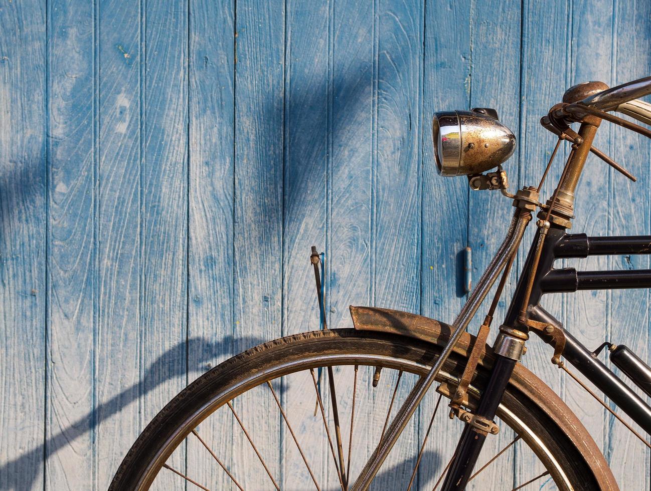 vecchia bicicletta parcheggiata davanti allo sfondo blu del pavimento della plancia foto