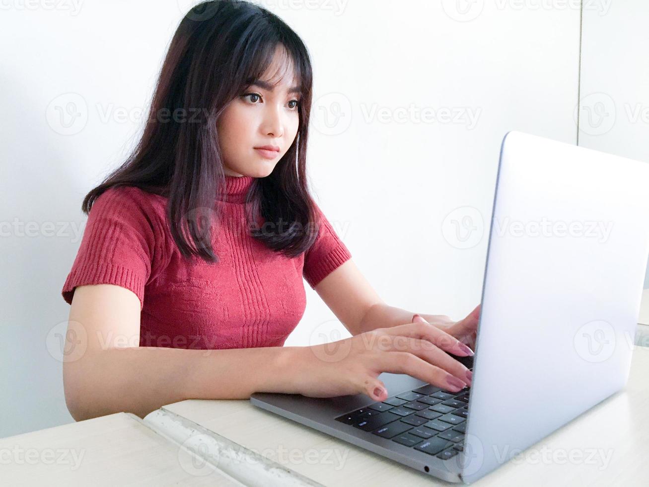 bella ragazza asiatica seria o pensando nella parte anteriore del laptop sullo sfondo bianco isolato foto