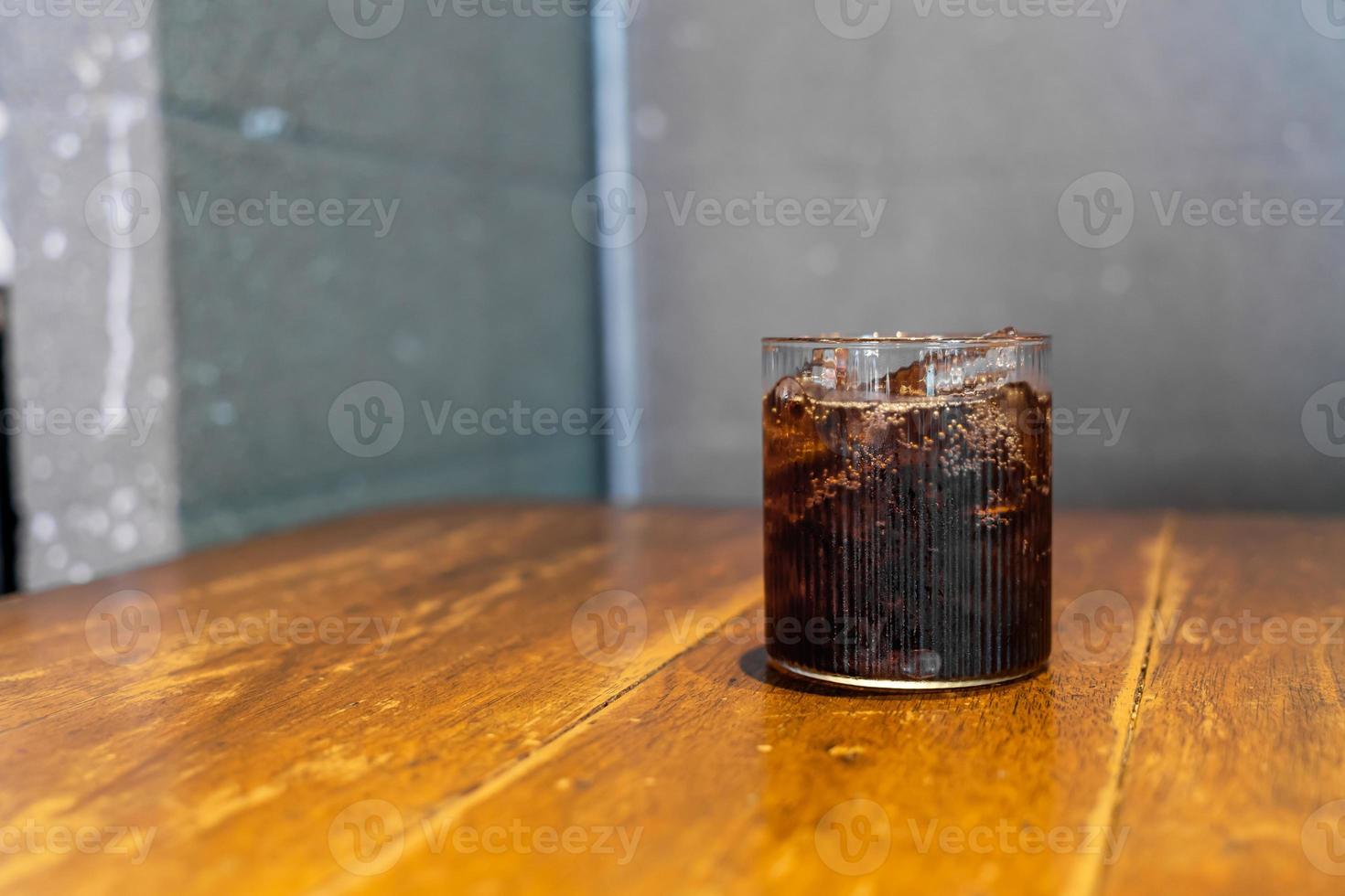 bicchiere di cola di ghiaccio sul tavolo foto