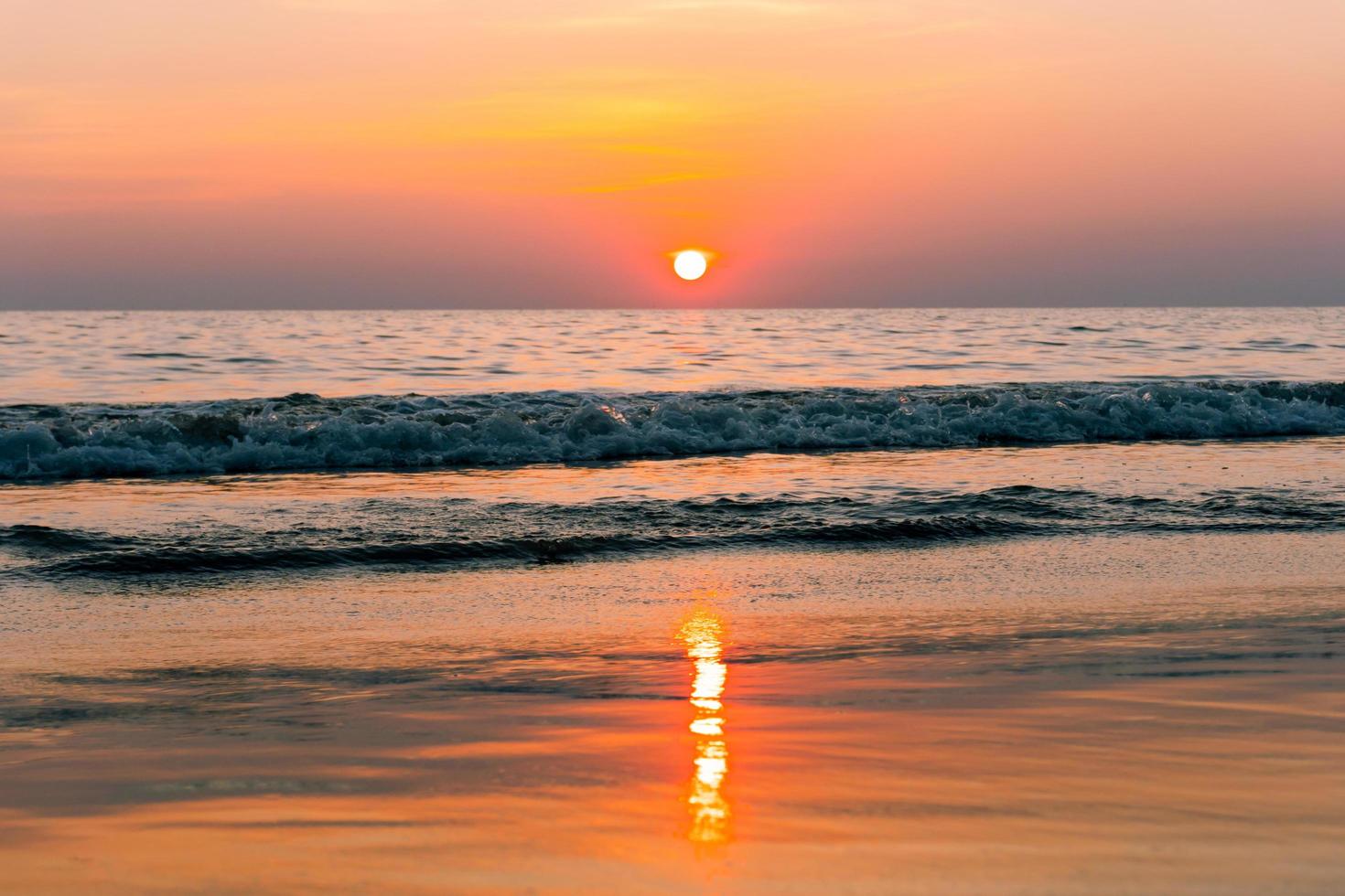 tramonto riflesso sul mare. bel tramonto dietro le nuvole e il cielo blu sopra lo sfondo del paesaggio del mare foto