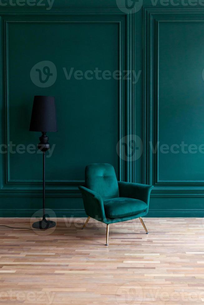 bella camera interna pulita di lusso classico blu verde in stile classico con poltrona morbida verde. sedia blu-verde antica d'epoca in piedi accanto al muro color smeraldo. design per la casa minimalista. foto