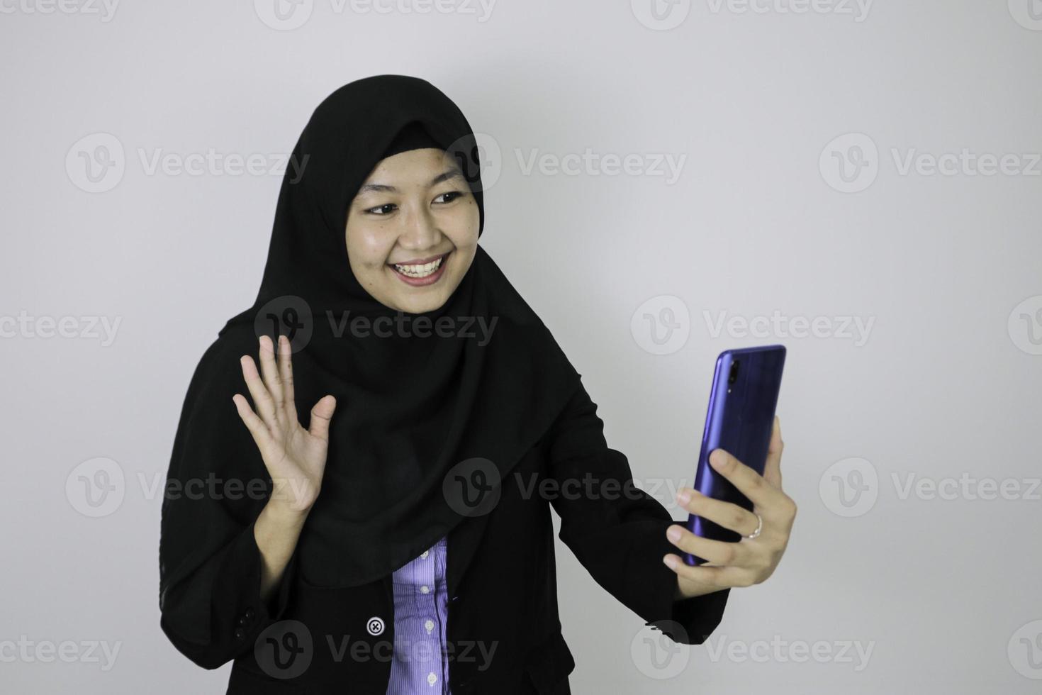 Sorriso asiatico islam donna che indossa il velo quando la videochiamata sul telefono foto