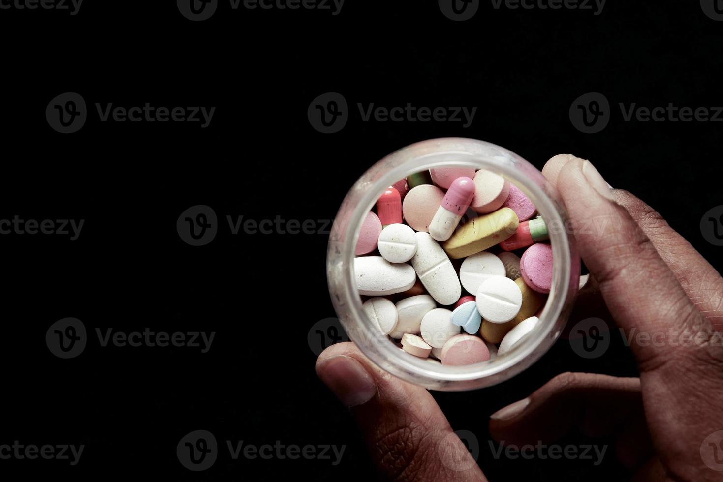 concetto di abuso di droghe con molte pillole a portata di mano su sfondo nero foto