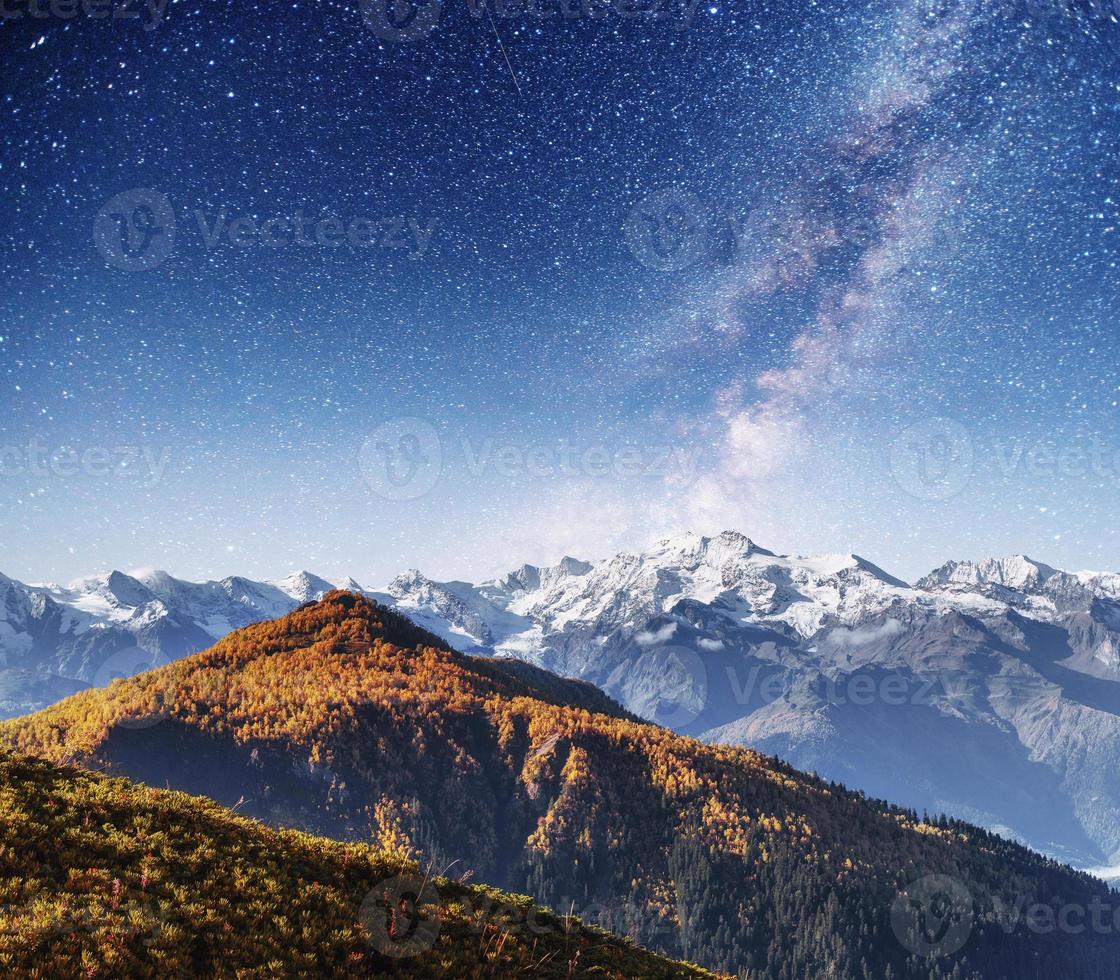 fantastico cielo stellato. paesaggio autunnale e cime innevate. ma foto