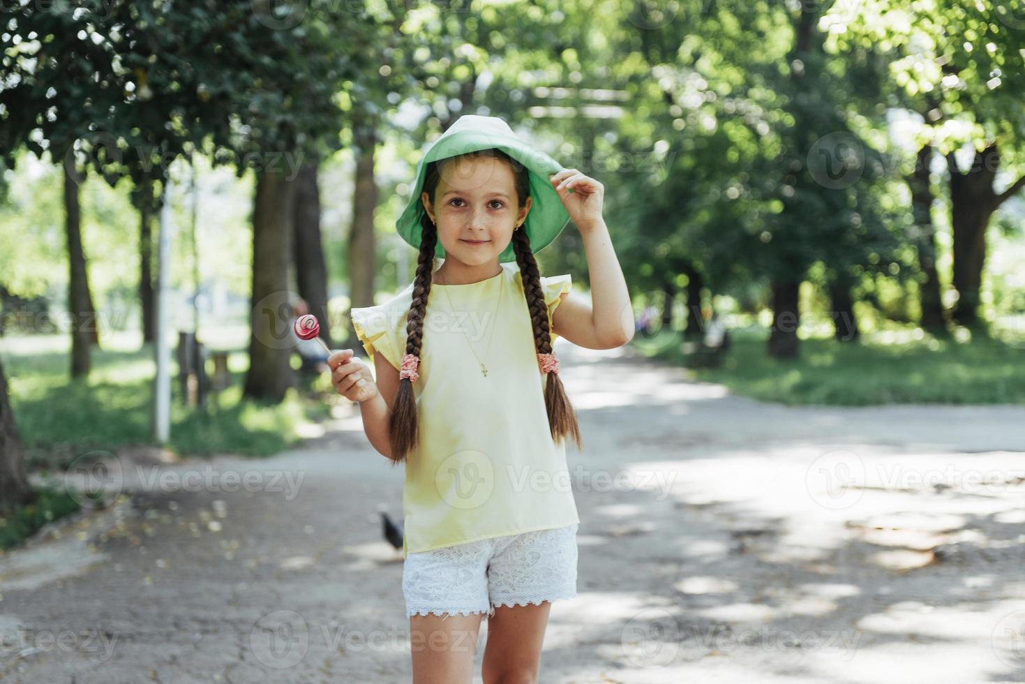 bambino divertente con lecca-lecca caramelle, bambina felice che mangia grande foto