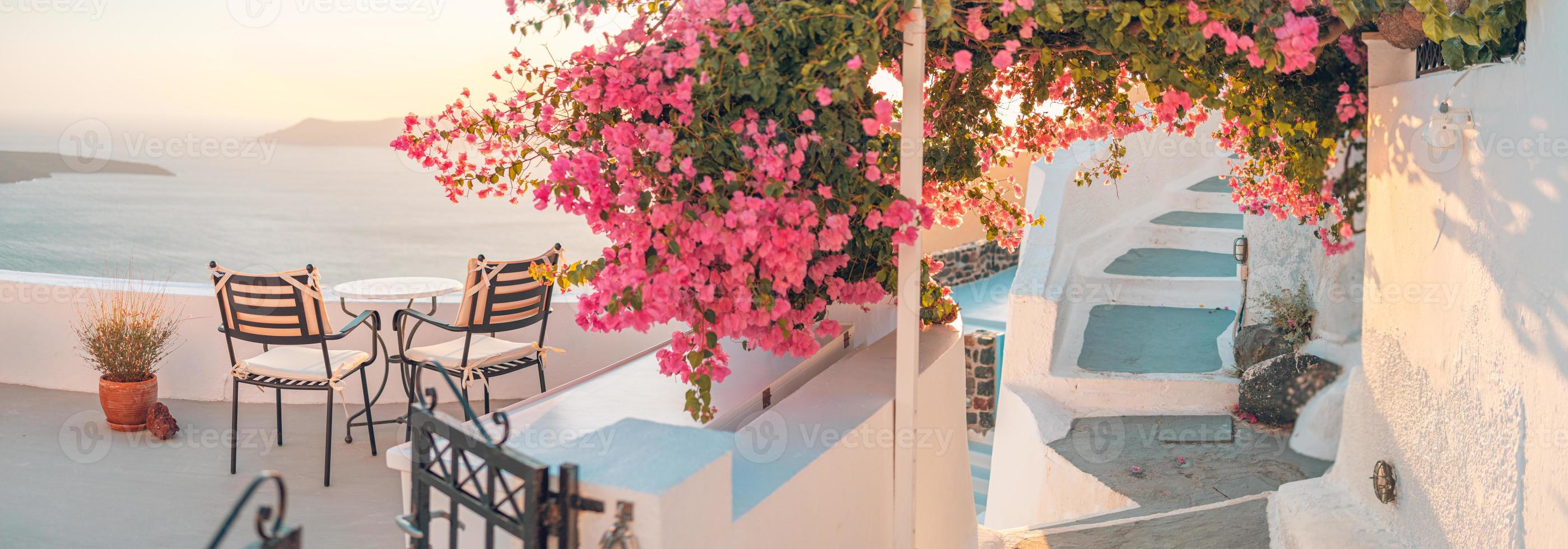 bella vista della caldera e godersi uno scenario romantico tramonto sul mar egeo, santorini. vacanza di viaggio di coppia, destinazione per la luna di miele. romanticismo con fiori, due sedie tavolo e vista mare. vacanza di lusso foto