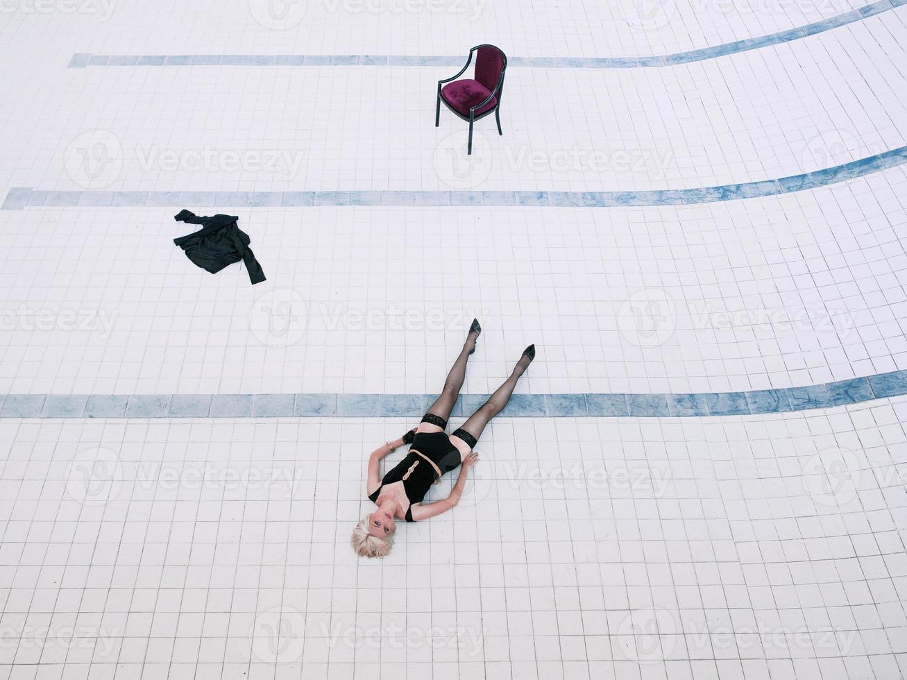 giovane donna in biancheria intima nera e calze da sola nella piscina vuota foto