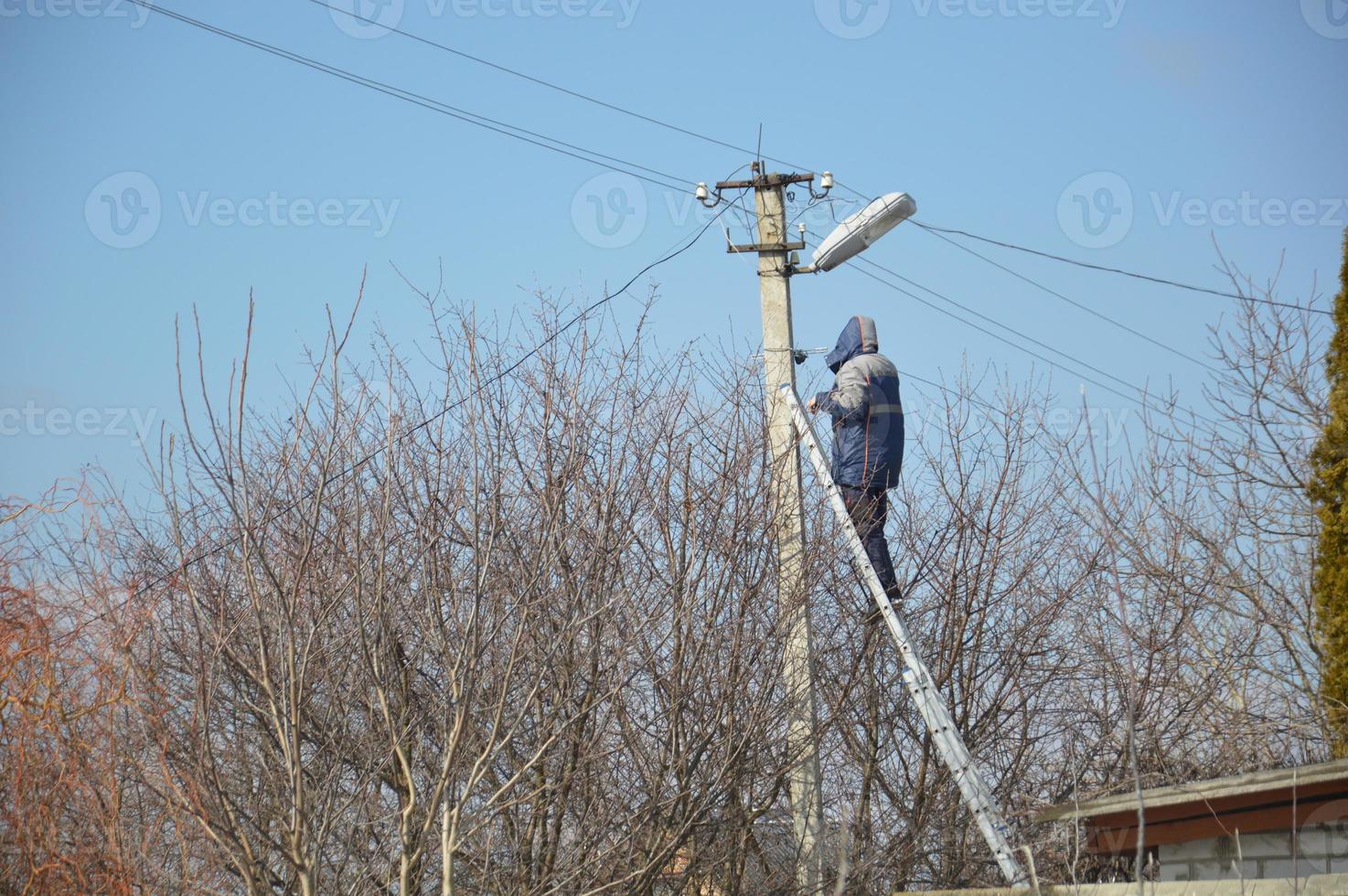 l'uomo si collega a Internet via cavo su un palo elettrico foto