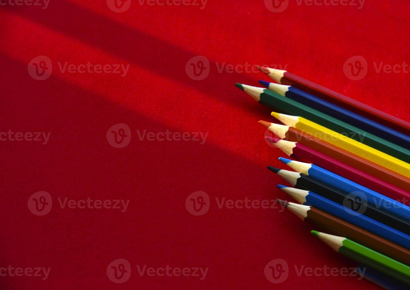 matite multicolori su sfondo rosso alla luce foto