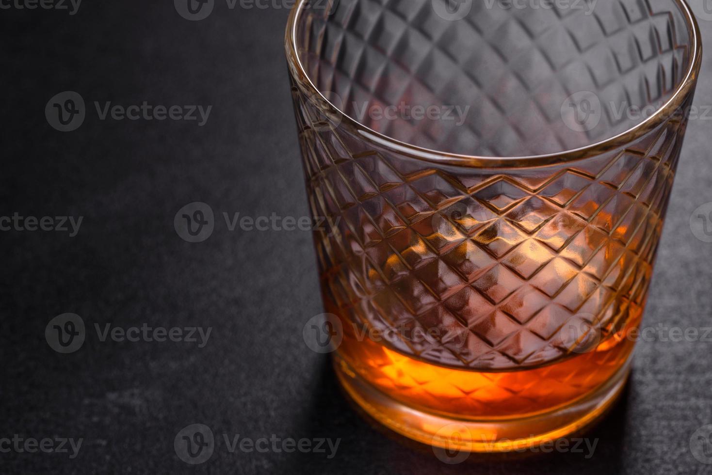 un bicchiere di whisky o cognac su un tavolo di cemento nero. momento relax foto