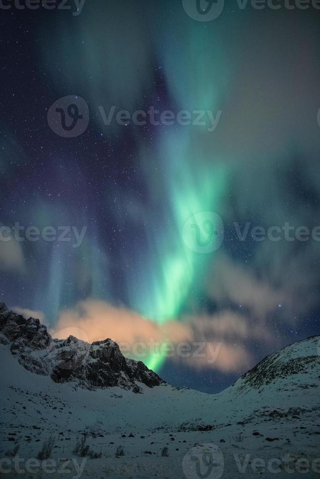 Aurora boreale, aorra boreale con stellata sulla cima della montagna innevata di notte foto