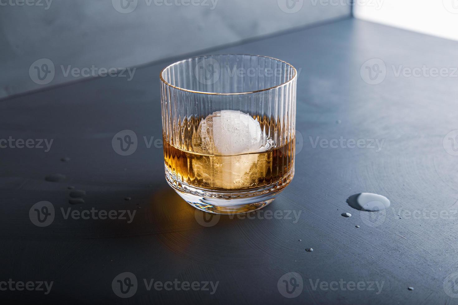 cubetto di ghiaccio a forma di sfera e vista ravvicinata del whisky dallo studio. foto