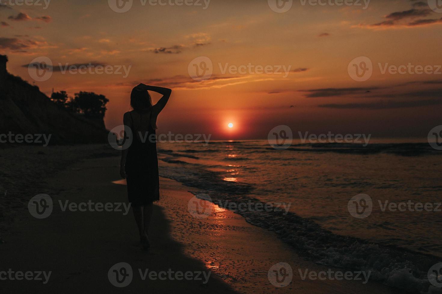 mattina alba la ragazza va in spiaggia al mattino. sagoma di ragazza al tramonto. la donna si rilassa in riva al mare. foto