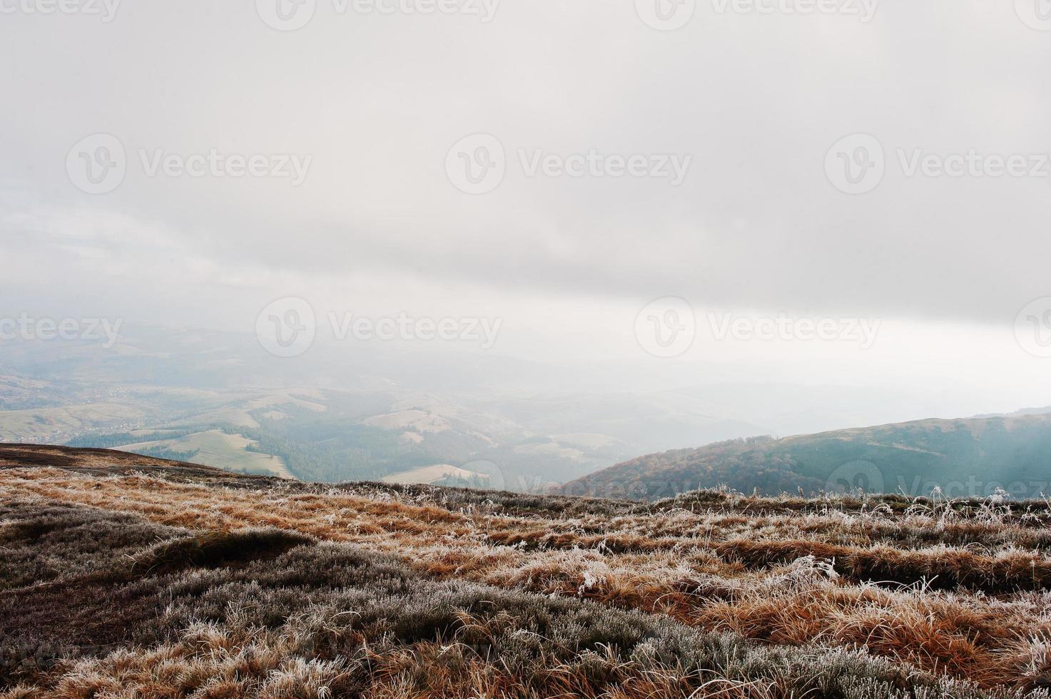 collina di montagna con erba gelata e luce solare dalle nuvole foto