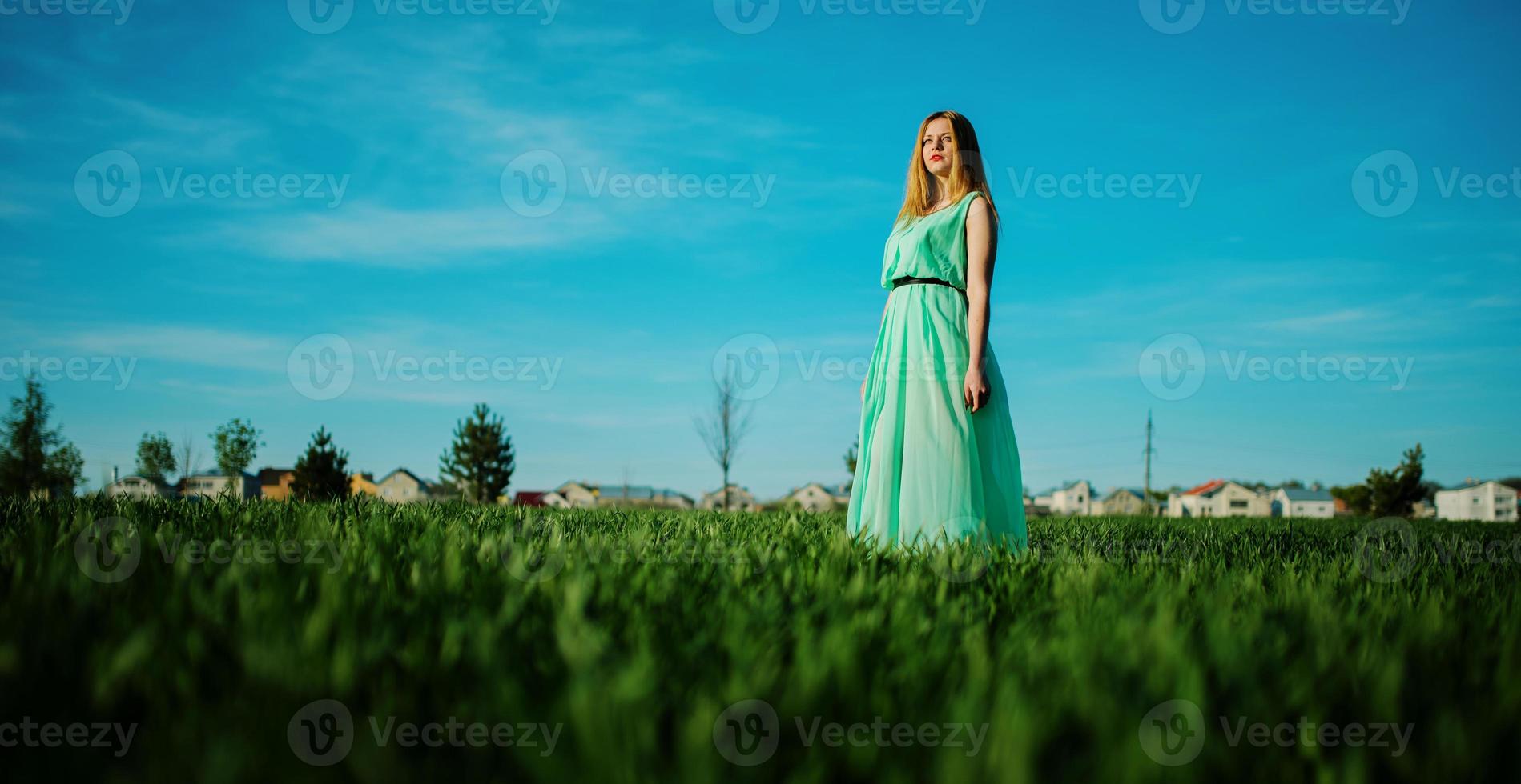 donna in un bel vestito lungo turchese in posa su un prato sull'erba. foto