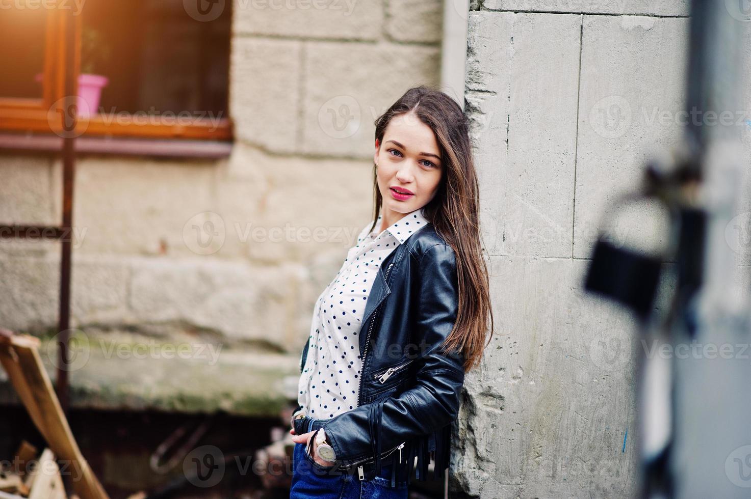 ritratto di ragazza alla moda indossare su giacca di pelle e jeans strappati per le strade della città. stile modello di moda di strada. foto