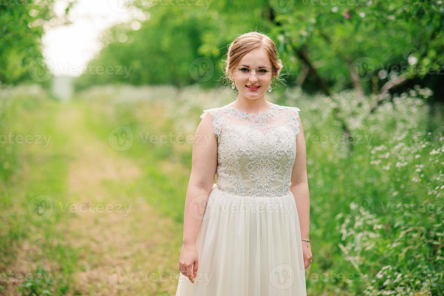 giovane ragazza in sovrappeso in abito beige poste sfondo giardino primaverile. foto