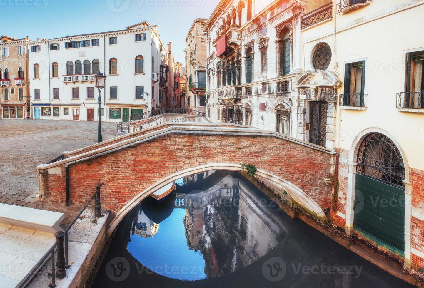 gondole tradizionali sul canale stretto tra case storiche colorate a venezia italia foto